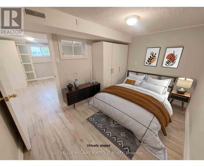 A bedroom with a bed, nightstand, and a window.