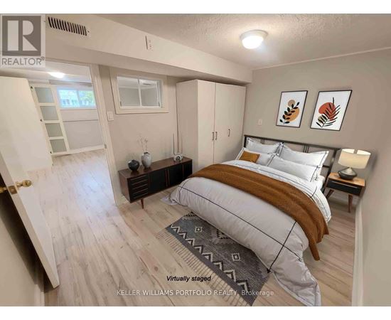 A bedroom with a bed, nightstand, and a window.