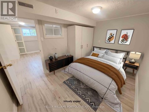 A bedroom with a bed, nightstand, and a window.