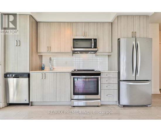A kitchen with a refrigerator, oven, and microwave.