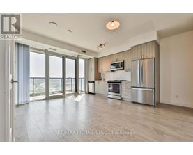 A spacious kitchen with stainless steel appliances and a flat screen TV mounted above the fridge.