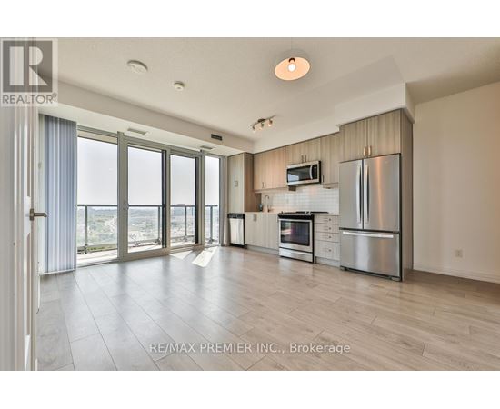 A spacious kitchen with stainless steel appliances and a flat screen TV mounted above the fridge.