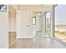 A room with a white door and a large window with a view of the city.