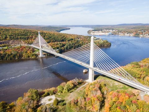 A bridge spans a river surrounded by trees in autumn colors.