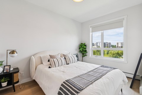 A bedroom with a large bed and a window overlooking a cityscape.