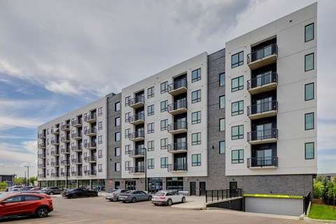 A modern apartment building with cars parked in front.