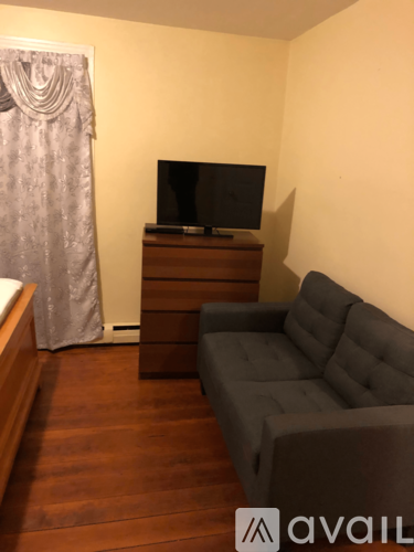 A living room with a grey couch and a television on a wooden cabinet.