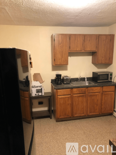 A kitchen with wooden cabinets and a black fridge.