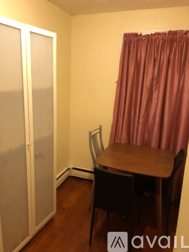 A room with a table and chairs and a curtain.