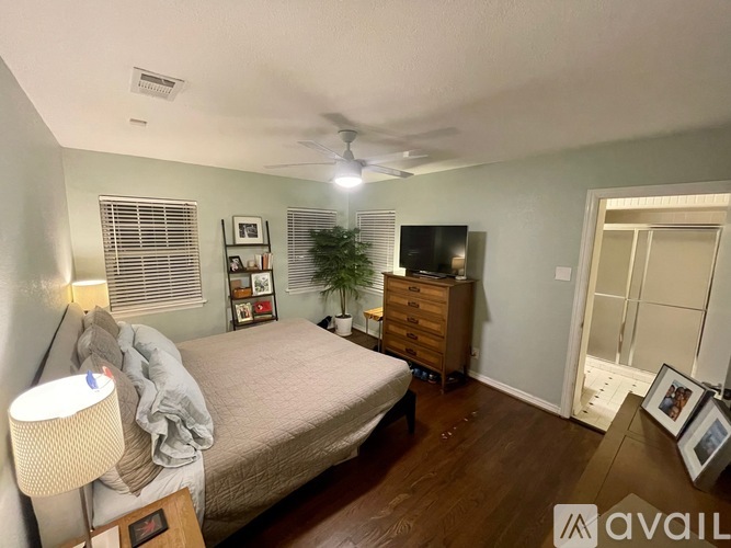 A bedroom with a bed, dresser, and a ceiling fan.