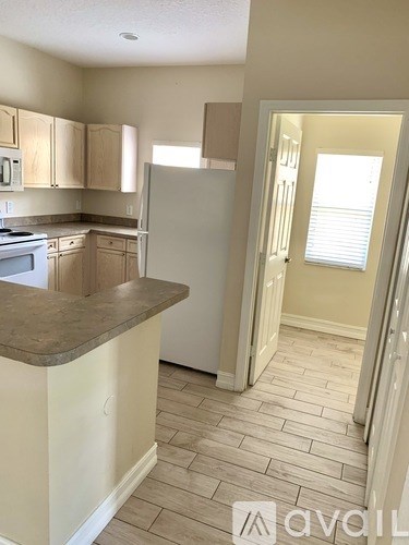 A kitchen with a refrigerator, cabinets, and a counter.