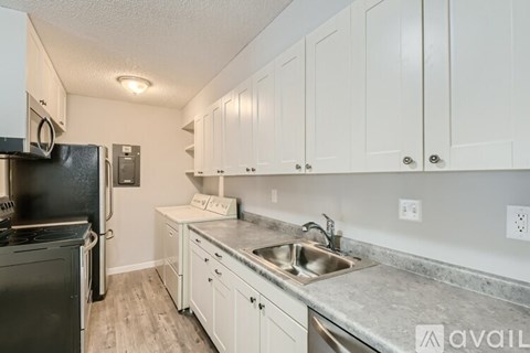 A kitchen with white cabinets and a black fridge.