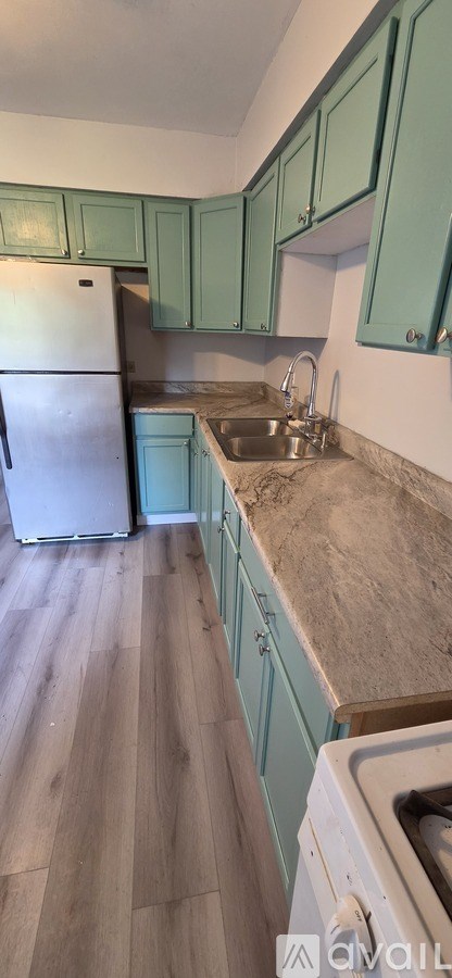 A kitchen with green cabinets and a white refrigerator.