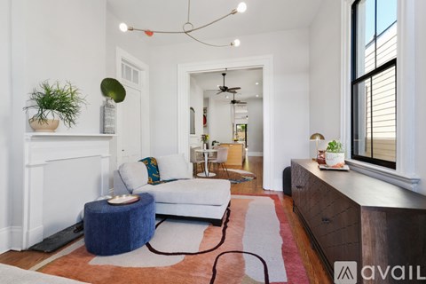 A living room with a white couch and a blue ottoman.