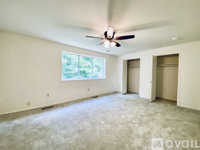 A spacious room with a ceiling fan and a large window.