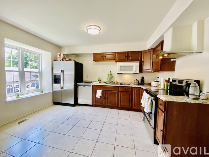 A kitchen with white tiled floors and wooden cabinets.
