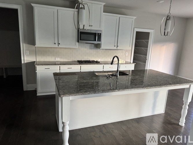 A kitchen with white cabinets and a granite countertop.