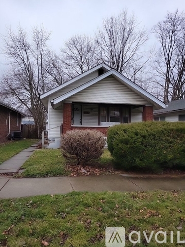 A house with a white front yard and a tree in the background.