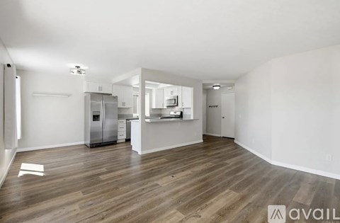 A spacious kitchen with a refrigerator, sink, and cabinets is available for rent.
