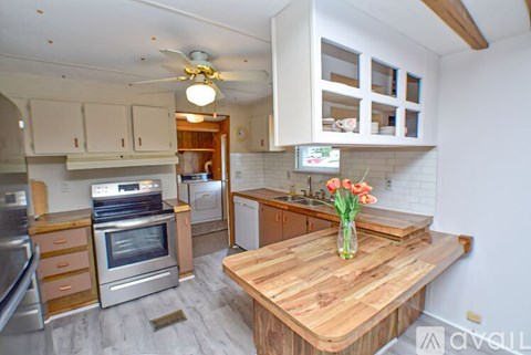 A kitchen with a wooden table and a vase of flowers on it.