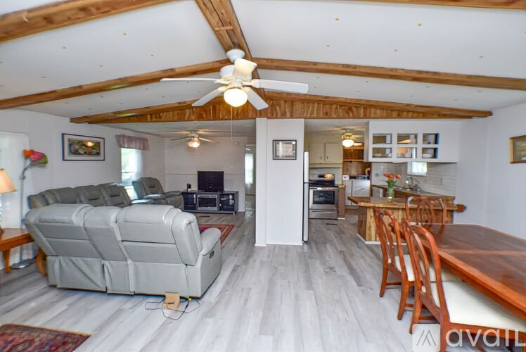 A living room with a couch, a television, and a ceiling fan.