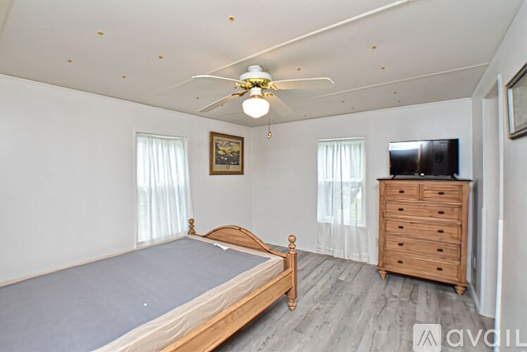 A bedroom with a bed, dresser, and television.