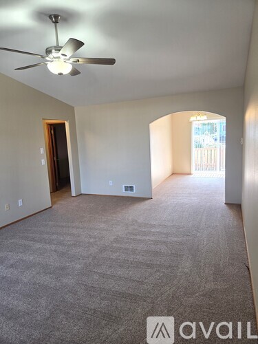 A room with a ceiling fan and carpeted floor.