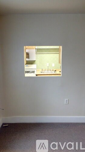 A room with a window showing a kitchen.