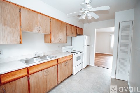 A kitchen with wooden cabinets and a white ceiling fan.