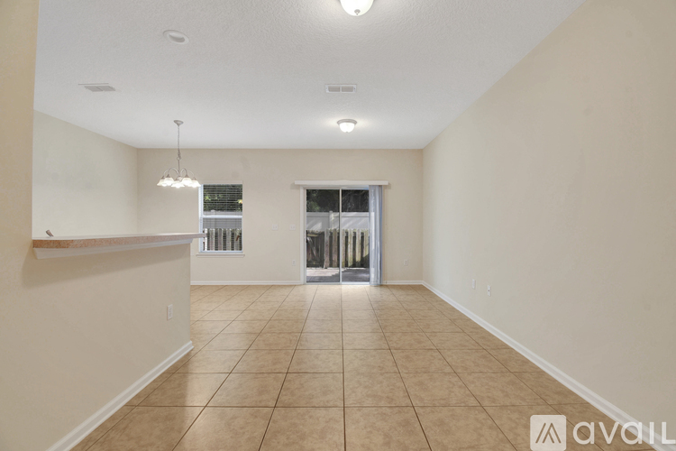 A spacious room with tiled flooring and a chandelier hanging from the ceiling.