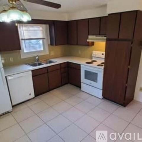 A kitchen with brown cabinets and white appliances.