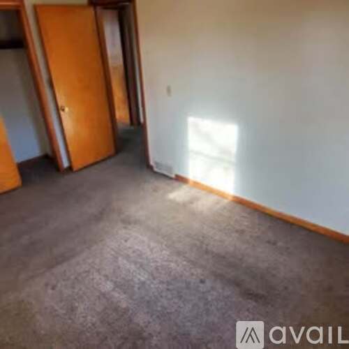 A room with a carpeted floor and a wooden door.