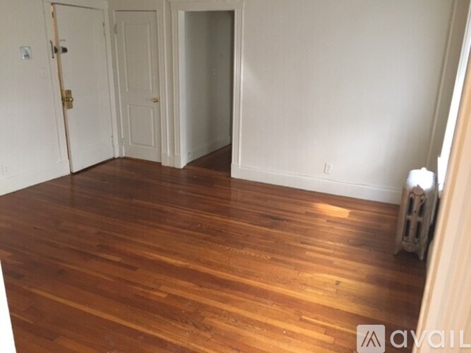 A room with wooden flooring and white walls.
