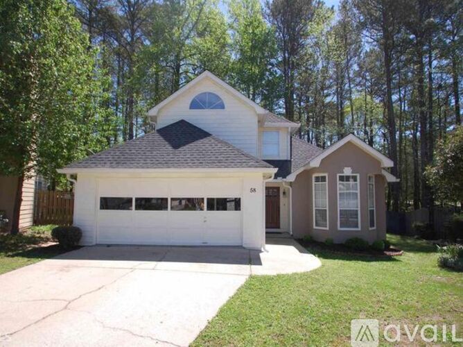 A two-story house with a garage is surrounded by trees.
