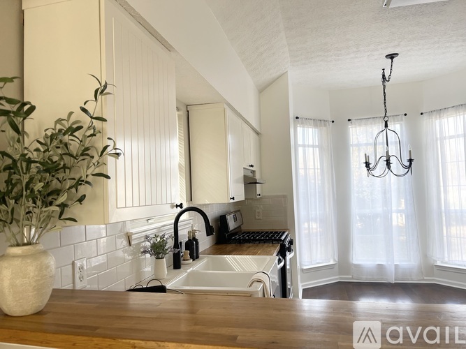 A kitchen with a wooden countertop and white cabinets.