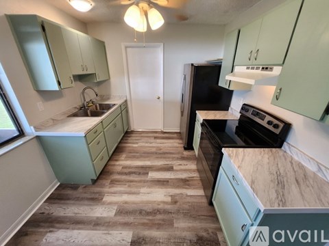 A kitchen with green cabinets and a black refrigerator.