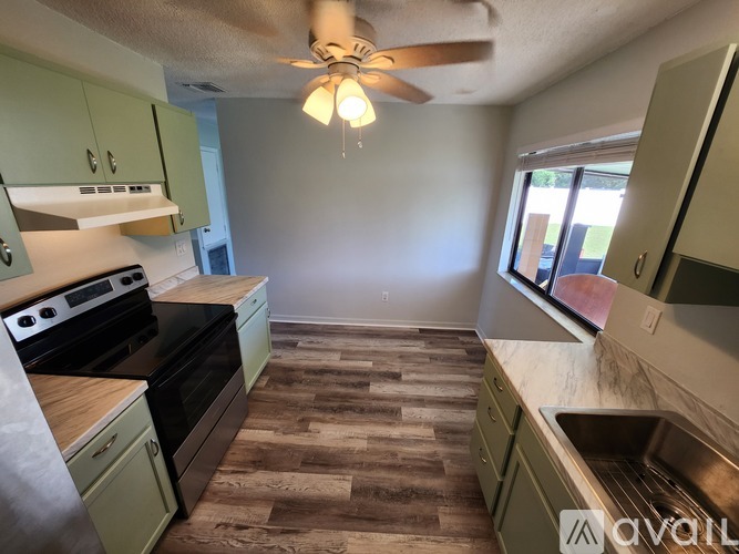 A kitchen with a wood floor and a ceiling fan.