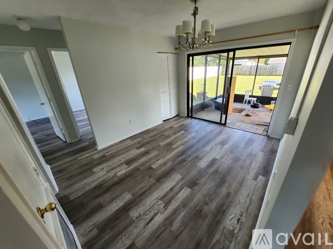 A room with wooden flooring and a chandelier.