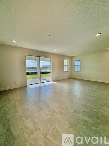A spacious room with tiled flooring and sliding glass doors leading to a balcony.