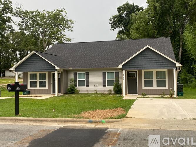 A house with a grey roof and a black mailbox in front.
