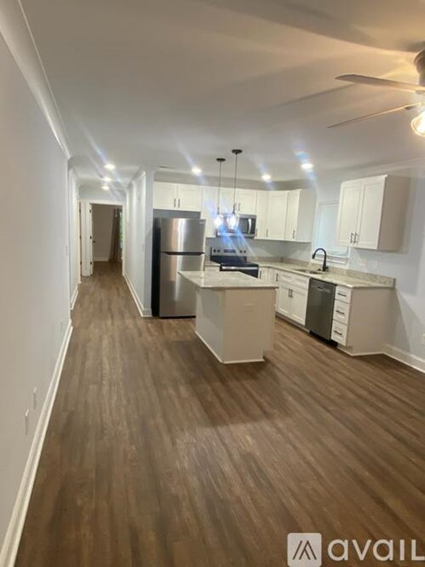 A kitchen with white cabinets and a wooden floor.