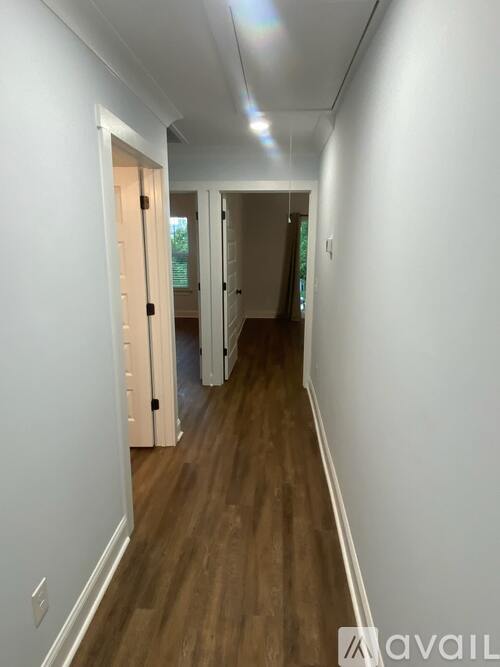 A long hallway with white walls and wood flooring.