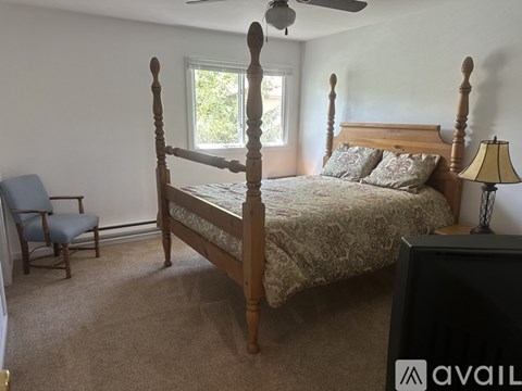 A bedroom with a four poster bed and a chair.