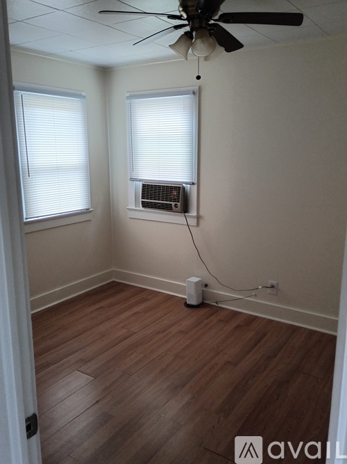 A room with a ceiling fan and wooden flooring.