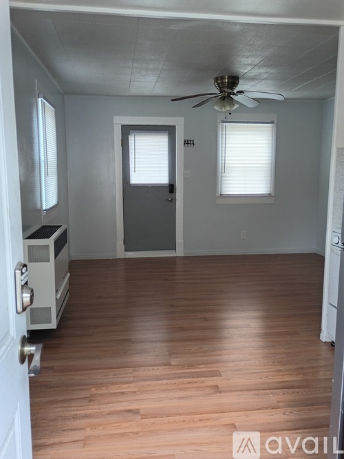 A room with a ceiling fan and wooden flooring.