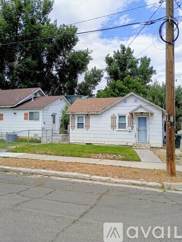 Two houses with a white and a beige exterior are situated on a street.