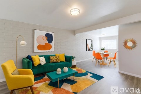 A living room with a green couch, yellow chair, and a painting on the wall.