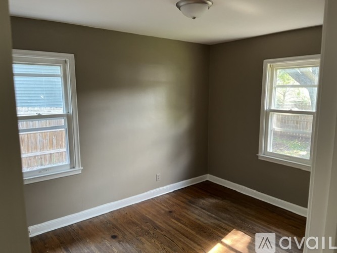 A room with wooden floors and two windows.