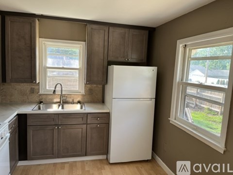 A kitchen with a white refrigerator and brown cabinets.