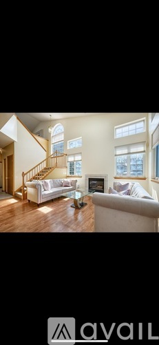 A living room with a couch, a coffee table, and a staircase.